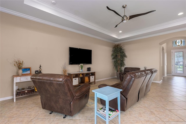 living area featuring ornamental molding, arched walkways, a raised ceiling, and light tile patterned floors