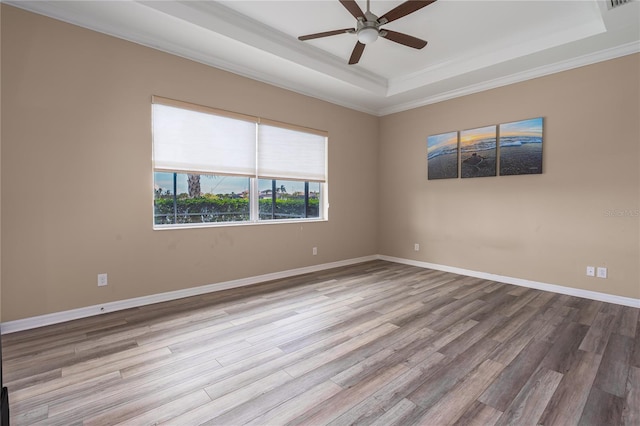 unfurnished room with visible vents, baseboards, a ceiling fan, a raised ceiling, and wood finished floors