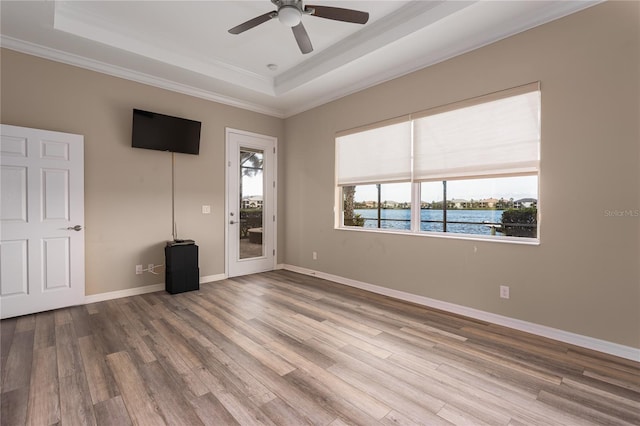 unfurnished room featuring a tray ceiling, ceiling fan, baseboards, and wood finished floors