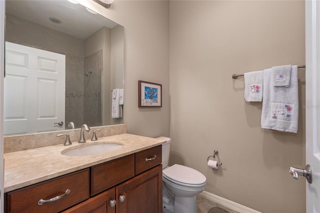 bathroom with toilet, baseboards, a tile shower, and vanity