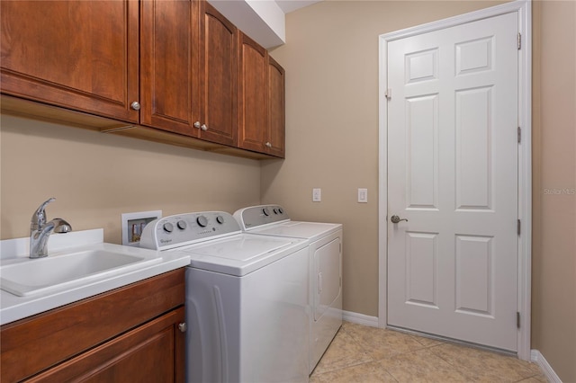 laundry room featuring light tile patterned flooring, a sink, baseboards, independent washer and dryer, and cabinet space