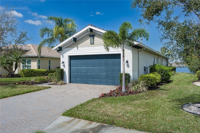 ranch-style home featuring a front lawn, decorative driveway, an attached garage, and stucco siding