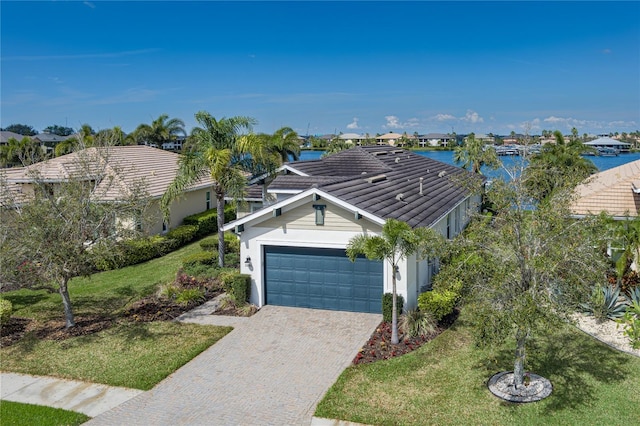 view of front of home with a garage, a tiled roof, a front lawn, and decorative driveway