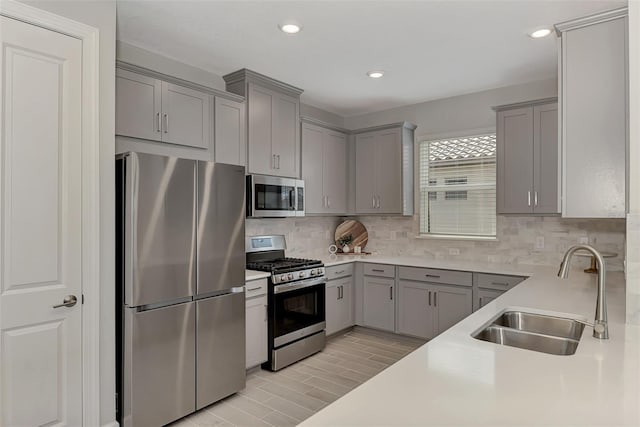 kitchen with stainless steel appliances, sink, backsplash, and gray cabinets