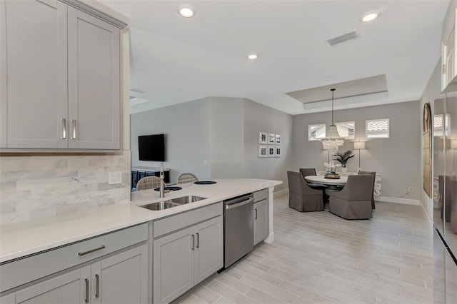 kitchen with sink, gray cabinets, dishwasher, a raised ceiling, and decorative backsplash