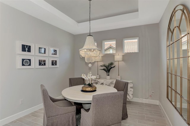 dining room with a notable chandelier and a tray ceiling