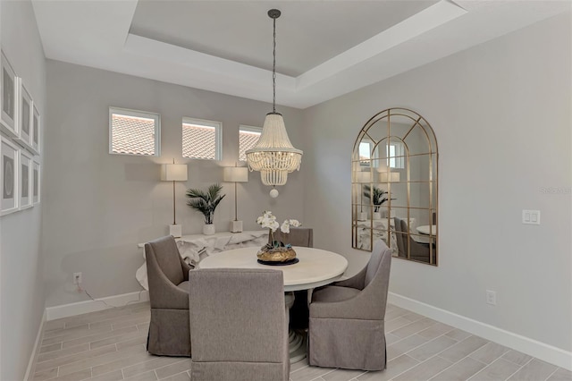 dining area with a notable chandelier and a tray ceiling