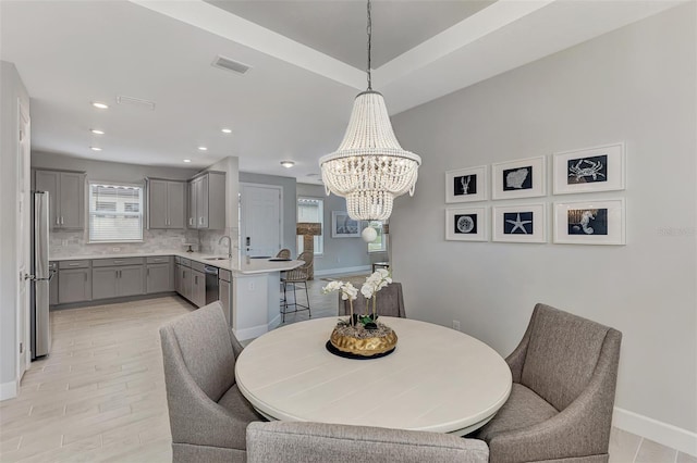 dining space featuring sink, an inviting chandelier, and light hardwood / wood-style floors