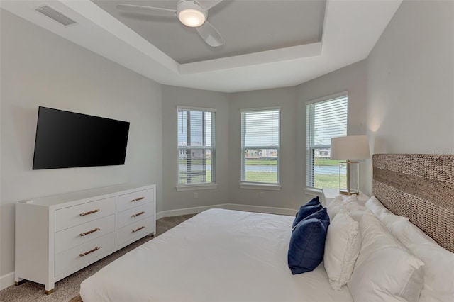 bedroom with a tray ceiling, ceiling fan, and carpet flooring