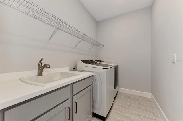 clothes washing area with sink, cabinets, and washer and dryer