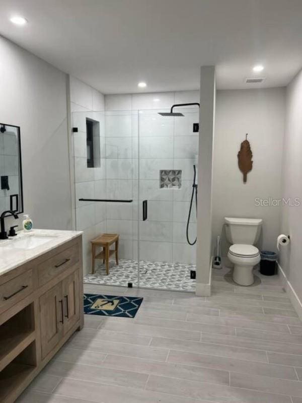 bathroom with toilet, vanity, and a shower with door