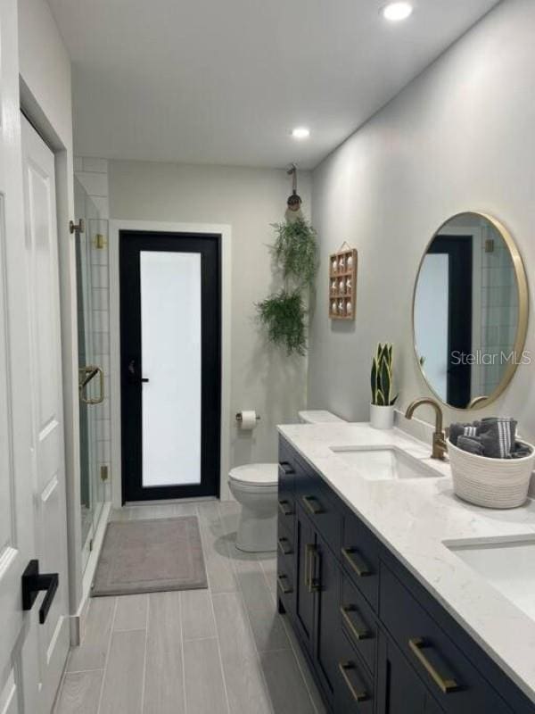 bathroom featuring toilet, an enclosed shower, and vanity