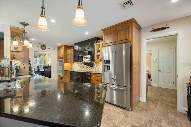 kitchen with sink, decorative light fixtures, appliances with stainless steel finishes, dark stone counters, and backsplash