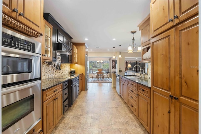 kitchen with sink, dark stone countertops, backsplash, hanging light fixtures, and stainless steel appliances