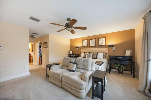 bedroom featuring a walk in closet, light colored carpet, and ceiling fan