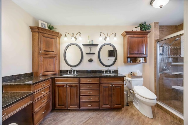 bathroom featuring a shower with door, vanity, and toilet