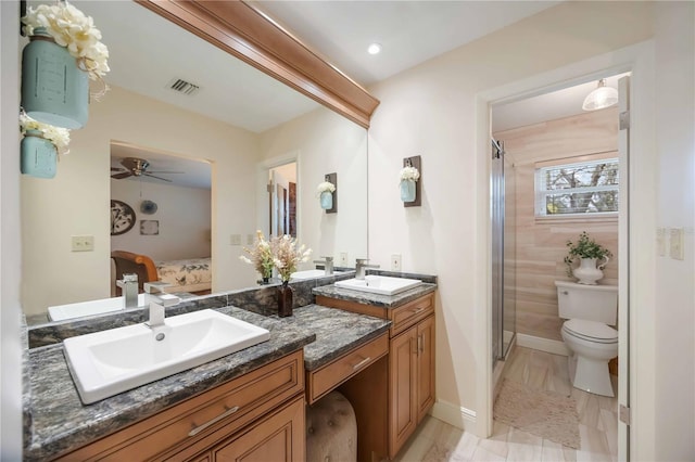 bathroom featuring ceiling fan, vanity, toilet, and an enclosed shower