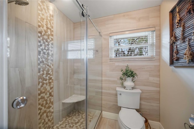 bathroom with a shower with shower door and toilet