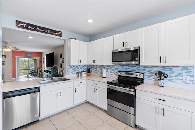 kitchen with sink, light tile patterned floors, appliances with stainless steel finishes, backsplash, and white cabinets