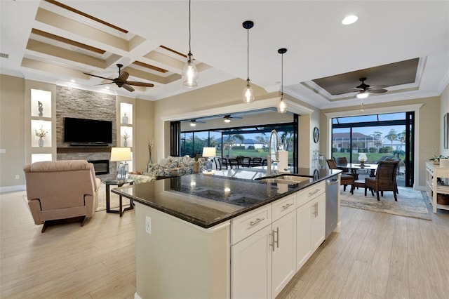 kitchen featuring an island with sink, open floor plan, dark stone countertops, white cabinetry, and pendant lighting