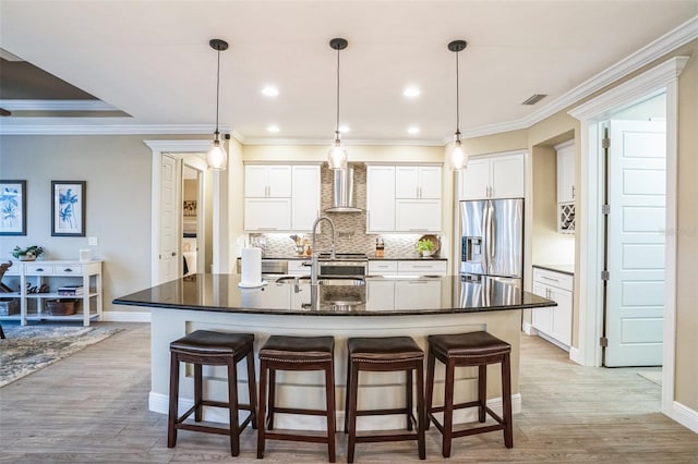 kitchen with decorative light fixtures, a spacious island, stainless steel fridge with ice dispenser, white cabinetry, and wall chimney exhaust hood