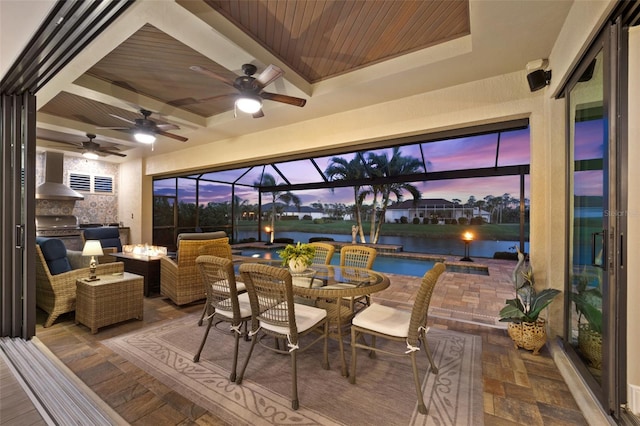 view of patio / terrace featuring ceiling fan, a lanai, an outdoor hangout area, area for grilling, and a water view