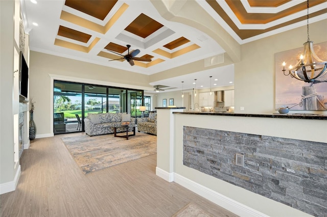 living room featuring arched walkways, coffered ceiling, ornamental molding, a high ceiling, and light wood-type flooring