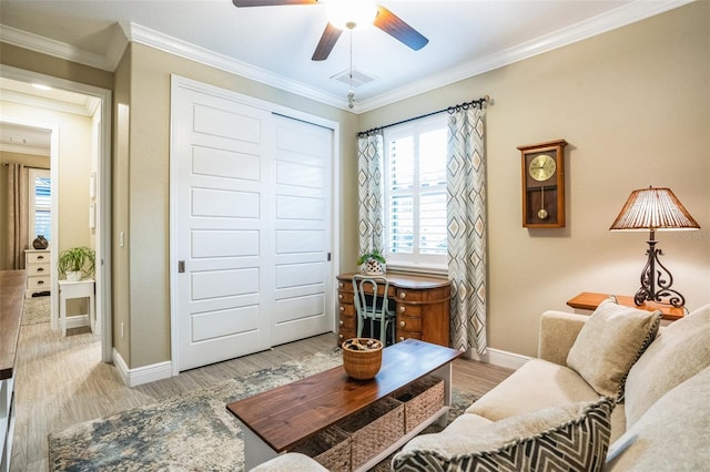 living room featuring light wood-type flooring, visible vents, baseboards, and crown molding