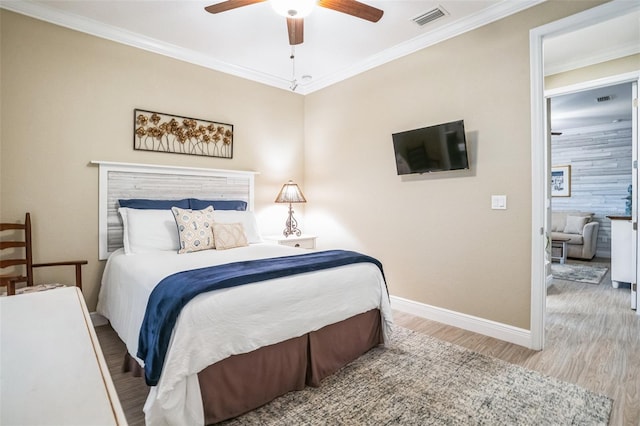 bedroom with baseboards, visible vents, a ceiling fan, wood finished floors, and crown molding