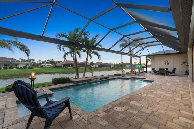 outdoor pool featuring glass enclosure, a patio, a fire pit, and a water view