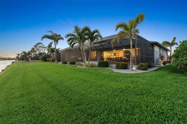 yard at dusk featuring a lanai and a water view