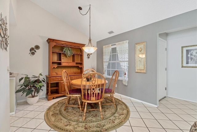 tiled dining space featuring vaulted ceiling