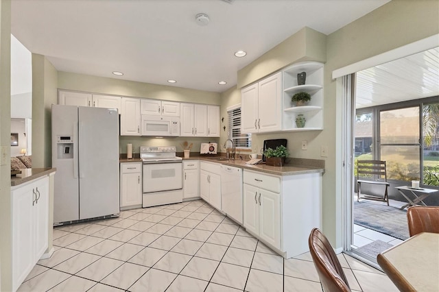 kitchen with white cabinetry, sink, light tile patterned floors, and white appliances