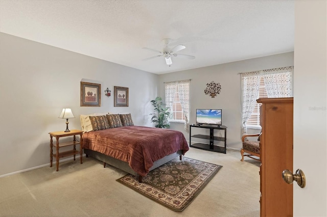 bedroom featuring ceiling fan, light carpet, and a textured ceiling