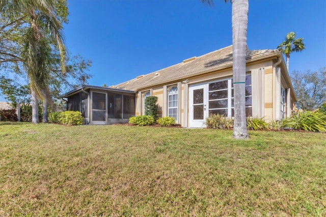 back of property featuring a lawn and a sunroom