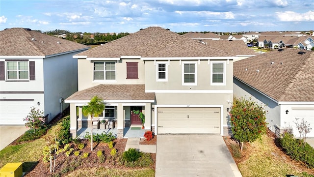 traditional home featuring concrete driveway, roof with shingles, covered porch, stucco siding, and a garage