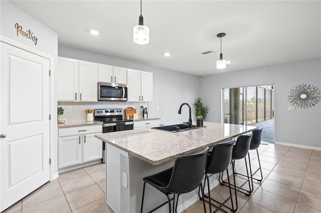 kitchen featuring sink, hanging light fixtures, a center island with sink, stainless steel appliances, and white cabinets