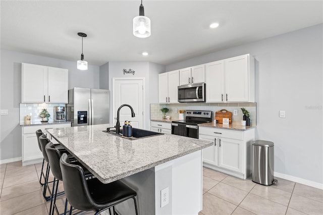 kitchen with sink, stainless steel appliances, an island with sink, and white cabinets