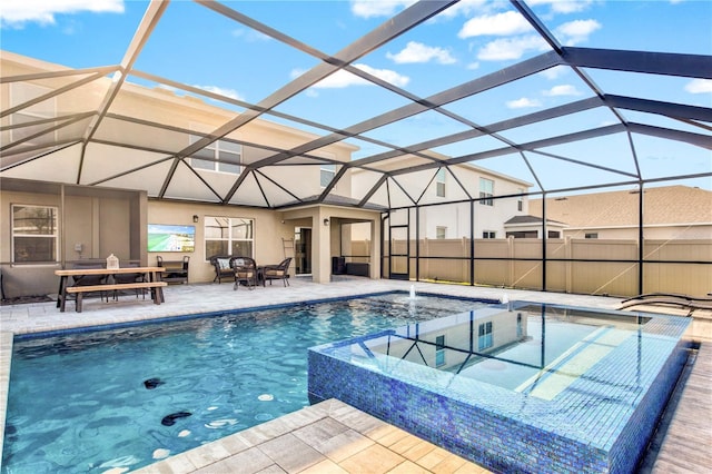 view of pool featuring an in ground hot tub, pool water feature, a patio area, and glass enclosure