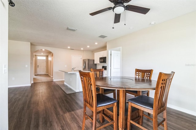 dining space with baseboards, visible vents, arched walkways, and dark wood-type flooring