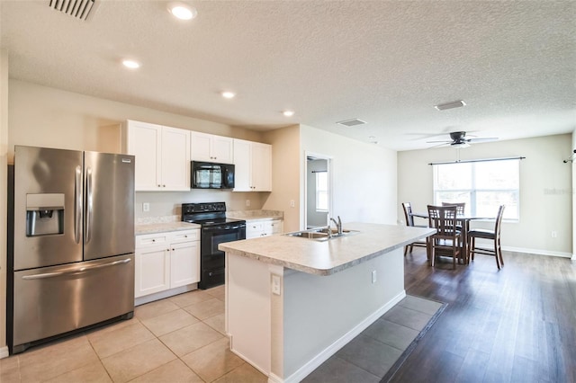 kitchen featuring a center island with sink, white cabinets, light countertops, black appliances, and a sink