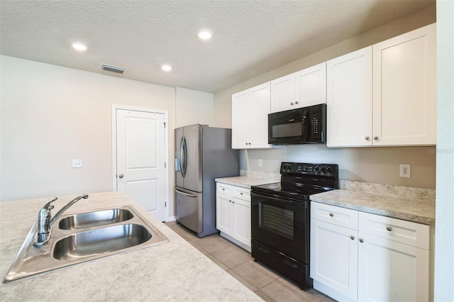 kitchen with a sink, visible vents, white cabinetry, light countertops, and black appliances