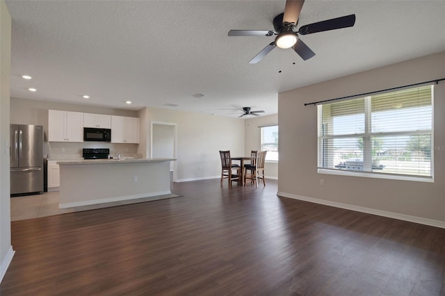 kitchen with a center island with sink, light countertops, open floor plan, white cabinets, and black appliances