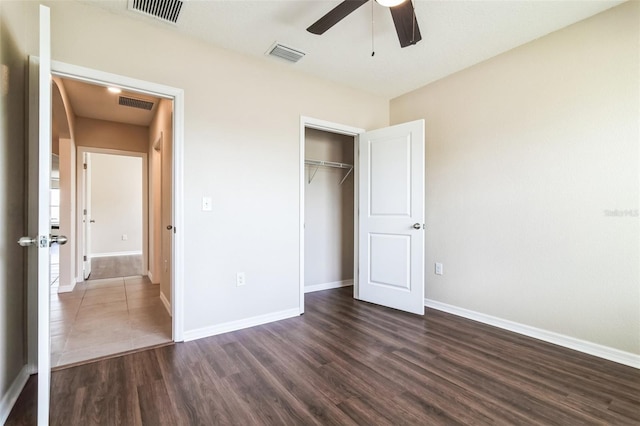 unfurnished bedroom with dark wood-style flooring, a closet, visible vents, and baseboards