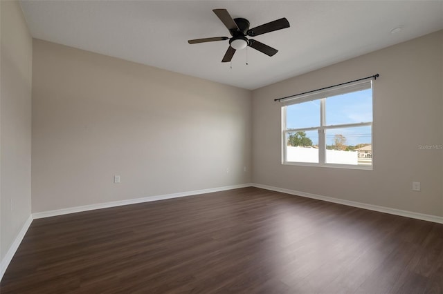 spare room with dark wood-style flooring, ceiling fan, and baseboards