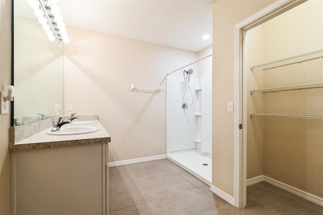 bathroom featuring double vanity, a stall shower, and baseboards