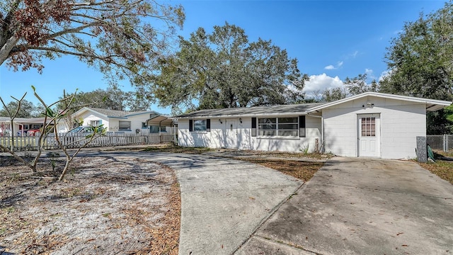 ranch-style home featuring a fenced front yard, concrete block siding, and concrete driveway