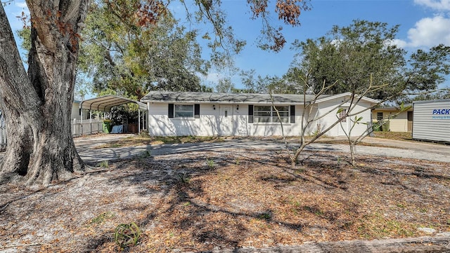 single story home featuring a detached carport, driveway, and fence