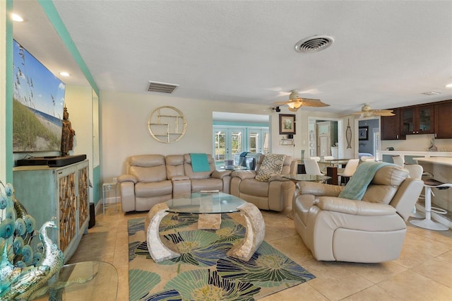 living room featuring light tile patterned flooring, ceiling fan, a textured ceiling, and french doors