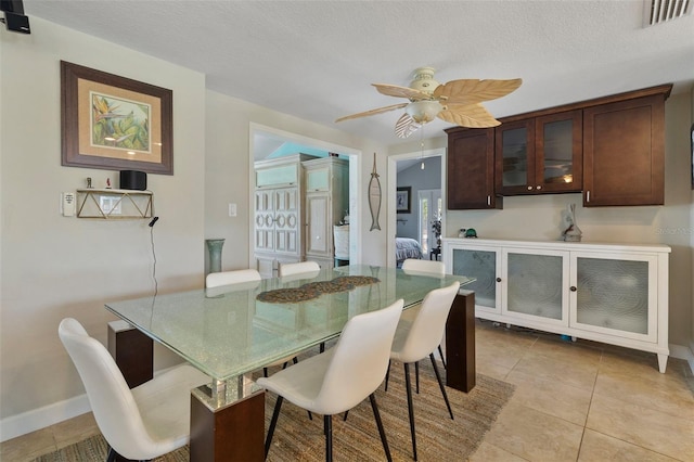 dining room with ceiling fan, a textured ceiling, and light tile patterned flooring